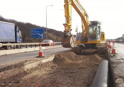 A New Holland E235B reduced tailswing tracked excavator at work on the motorway 