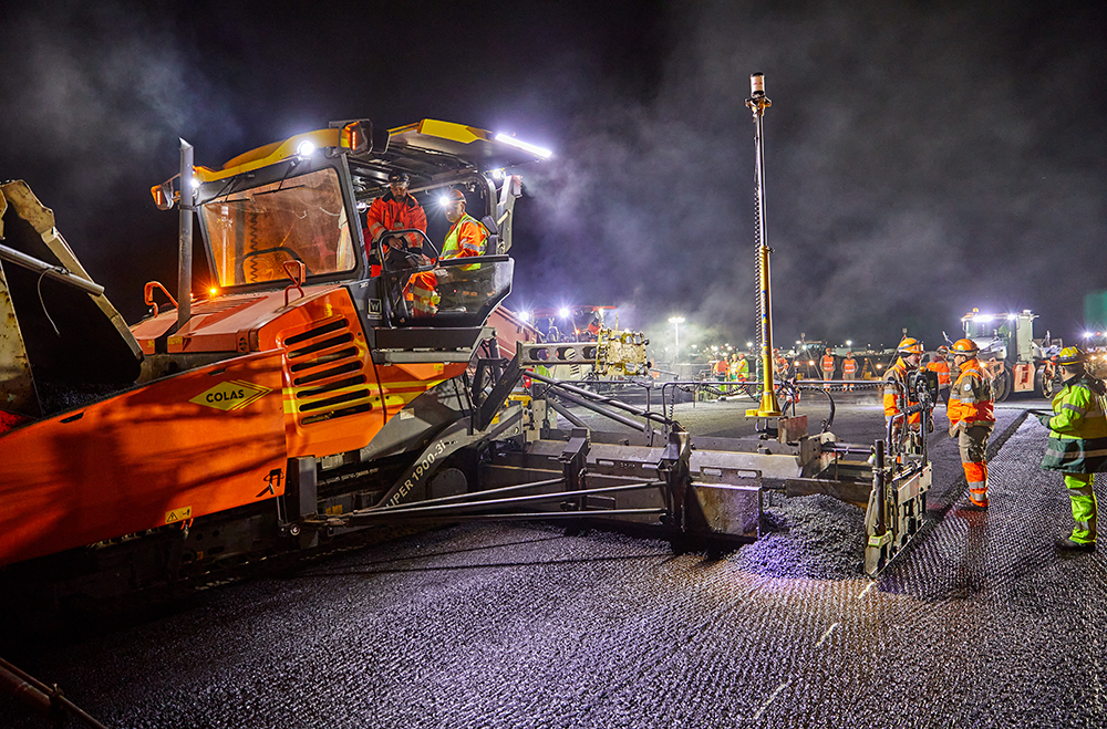 A paver equipped with two TrimbleMT900 Machine Targets begins laying asphalt, to the left of the axis of the runway - Photo La Compagnie Générale de Photographie 